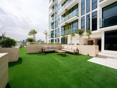 an apartment patio with green grass in a building at Crisp And Curated 1br With Pool, Gym And Parking! in Dubai