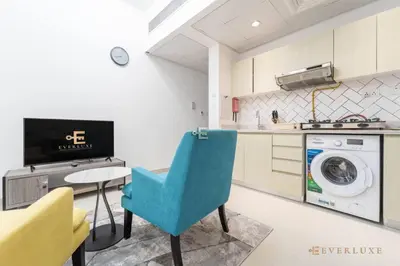 a kitchen with a washing machine and a blue chair at Perfect Midtown Studio Bright & Stylish in Dubai