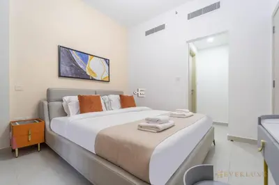 a white bedroom with a large bed with towels on it at Stylish 1br In Midtown Impz Soft Modern Vibes in Dubai