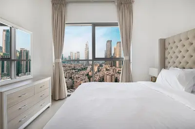 a bedroom with a white bed and a large window at Luxury 2,5BR Burj Khalifa Views with Pool and Gym Access Near Dubai Mall in Dubai