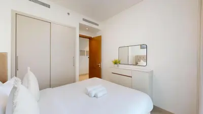 a bedroom with a white bed and a mirror at Creek Vistas - Elegant One Bedroom in Meydan in Dubai