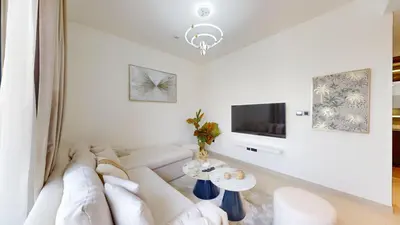 a white living room with a white couch and a tv at Creek Vistas - Elegant One Bedroom in Meydan in Dubai