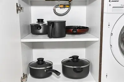 four pots and pans on a shelf in a kitchen at Modern Studio Steps from Iconic Dubai Mall & World-Class Amenities in Dubai