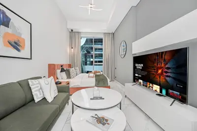a living room with a couch and a flat screen tv at Modern Studio Steps from Iconic Dubai Mall & World-Class Amenities in Dubai