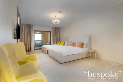 a bedroom with a white bed and a yellow chair at Bespoke Holiday Homes - Spacious 2BR Luxury Apartment with Stunning Palm Views, Balqis in Dubai