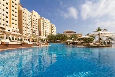 a large swimming pool in a resort with umbrellas at Bespoke Holiday Homes - Spacious 2BR Luxury Apartment with Stunning Palm Views, Balqis in Dubai