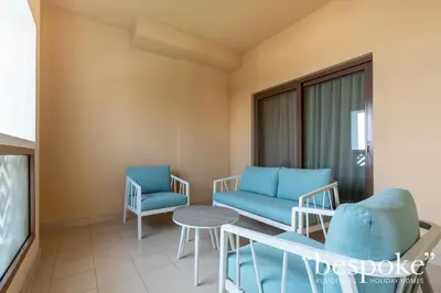 a living room with two chairs and a table at Bespoke Holiday Homes - Spacious 2BR Luxury Apartment with Stunning Palm Views, Balqis in Dubai