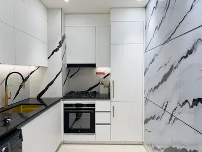 a kitchen with white cabinets and black appliances at Brand New with Private Jacuzzi in Dubai