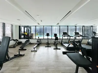 a gym with treadmills and ellipticals in a room with windows at 1-Bedroom Apartment in Downtown with Pool View in Dubai