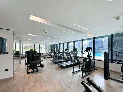 a gym with a row of treadmills and ellipticals at 1-Bedroom Apartment in Downtown with Pool View in Dubai