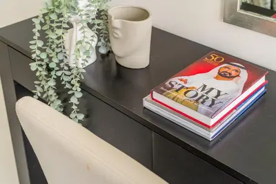 a black desk with a book and a vase at The Smart Concierge - Damac 108 in Dubai