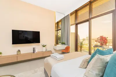 a bedroom with a large bed and a tv on a wall at Escape24 Cozy Studio with Infinity Pool in JVC in Dubai