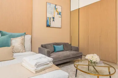 a living room with a couch and a chair at Escape24 Cozy Studio with Infinity Pool in JVC in Dubai