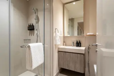 a bathroom with a shower and a sink and a mirror at Seraya Residence 20 - 4BDR - Burj View with direct access to Dubai Mall in Dubai
