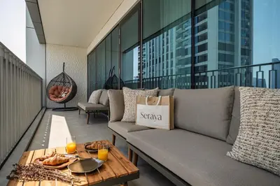 a balcony with a couch and a table on a building at Seraya Residence 21 - 4BDR - Cozy terrace with Burj Views in Dubai