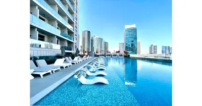 a swimming pool with white chairs and a city skyline at Stylish Studio - 5-min walk Burj Khalifa & Dubai Mall in Dubai