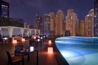 a swimming pool with tables and chairs and a city skyline at Luxury Studio Near Beach and Sea in Dubai Marina in Dubai