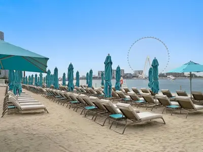 a row of chairs and umbrellas on a beach at Stylish 1BR Apartment in JBR with Beach Access & Dubai Marina Views in Dubai