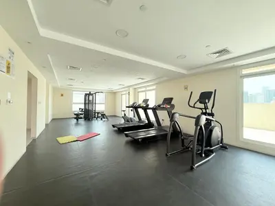 a gym with several treadmills and elliptical machines at Zapbed House-Stylish 2 BR in May Residence Block 1 -JVC in Dubai