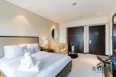a bedroom with a large white bed and a chair at The Cozy in Dubai