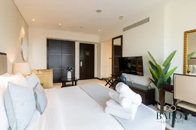 a bedroom with a white bed and a flat screen tv at The Cozy in Dubai