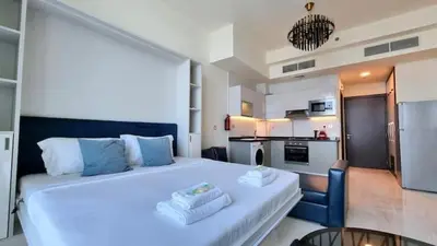 a bedroom with a large white bed and a kitchen at Business Bay, Compact, Modern Studio Dubai in Dubai