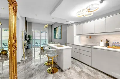 a kitchen with white cabinets and a gold mirror at Waves - Gold Opulence 1 BR in Marina in Dubai