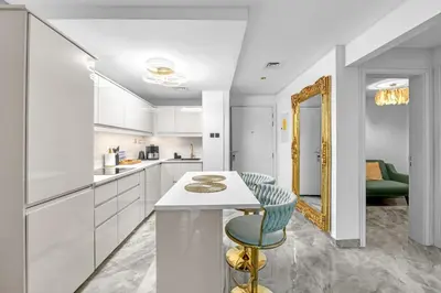 a white kitchen with a counter and a mirror at Waves - Gold Opulence 1 BR in Marina in Dubai