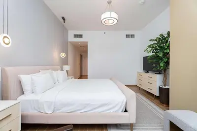 a bedroom with a white bed and a tv at 2BR Waterfront Apartment Nr Downtown in Dubai
