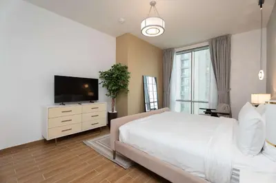 a bedroom with a bed and a flat screen tv at 2BR Waterfront Apartment Nr Downtown in Dubai