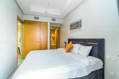 a bedroom with a large white bed with an orange pillow at Cozy 2BR Pool & City Views in Dubai