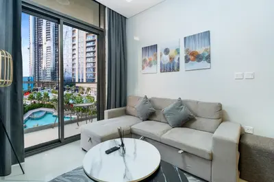 a living room with a couch and a large window at Cozy 2BR Pool & City Views in Dubai