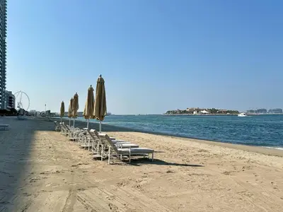 a row of chairs and umbrellas on a beach at Modern & Cozy 1BR with Great Amenities, Grand Bleu in Dubai