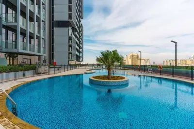 a large swimming pool with a palm tree in the middle at HAVN - High Floor Studio in Bloom Towers, JVC in Dubai