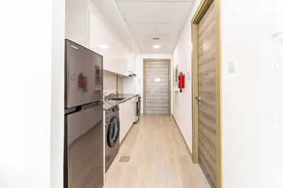a kitchen with a refrigerator and a washer and dryer at HAVN - High Floor Studio in Bloom Towers, JVC in Dubai