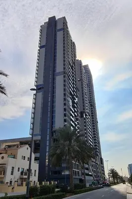 a tall building with a palm tree in front of it at HAVN - High Floor Studio in Bloom Towers, JVC in Dubai