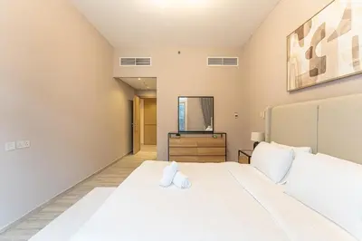 a bedroom with a large white bed and a mirror at HAVN - 1 Spacious Bedroom in Belgravia 1, JVC in Dubai