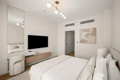 a white bedroom with a bed and a flat screen tv at DAYF-ROD Luxurious 2 Bed Apartment in Souk Al Bahar in Dubai