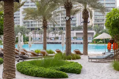 a resort with palm trees and chairs and a pool at Maison Privee - Creekside Elegance with Canal Vws at Creek Beach in Dubai
