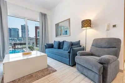 a living room with a couch and a chair at Urban Comfort 1Bedroom with Pool View in Oxford in Dubai