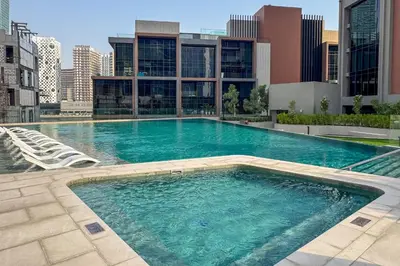 a large swimming pool in the middle of a city at Bright 1 Bedroom with Burj Khalifa view in Peninsula in Dubai
