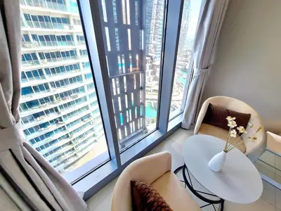 a living room with two windows and a table and chairs at Luxury 2BR in Cayan Tower with Stunning Views in Dubai