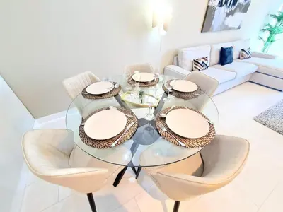 a dining room with a glass table and chairs at Luxury 2BR in Cayan Tower with Stunning Views in Dubai