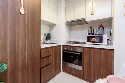 a small kitchen with wooden cabinets and a microwave at Tropical Nest in Dubai