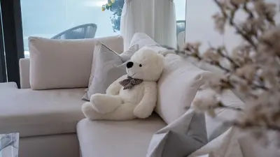 a teddy bear sitting on a white couch at Most Luxurious 2BR Apt Beach Access & Palm View in Dubai
