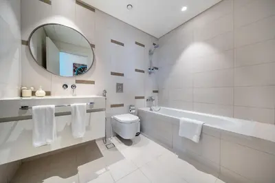 a bathroom with a tub and a toilet and a mirror at Most Luxurious 2BR Apt Beach Access & Palm View in Dubai