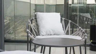 a wicker chair with a pillow and a table at Luxe Haven 1BR8min drive DubaiMall & BurjKhalifa in Dubai