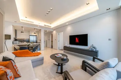 a living room with white furniture and a tv on a wall at Luxury Comfort 1BRNear Dubai Mall & Burj Khalifa in Dubai