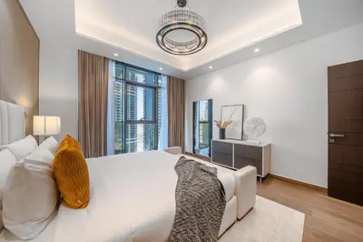 a bedroom with a white bed and a chandelier at Sky-High 2BR Escape Stylish Stay Near Dubai Mall in Dubai
