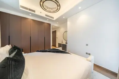 a bedroom with a white bed and a wall at Sky-High 2BR Escape Stylish Stay Near Dubai Mall in Dubai